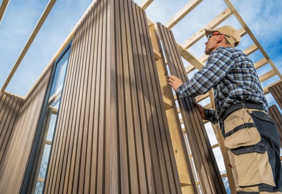 Caucasian General Construction Worker in His 40s Building Small Modern Garden Shed Using Wood and Composite Materials.